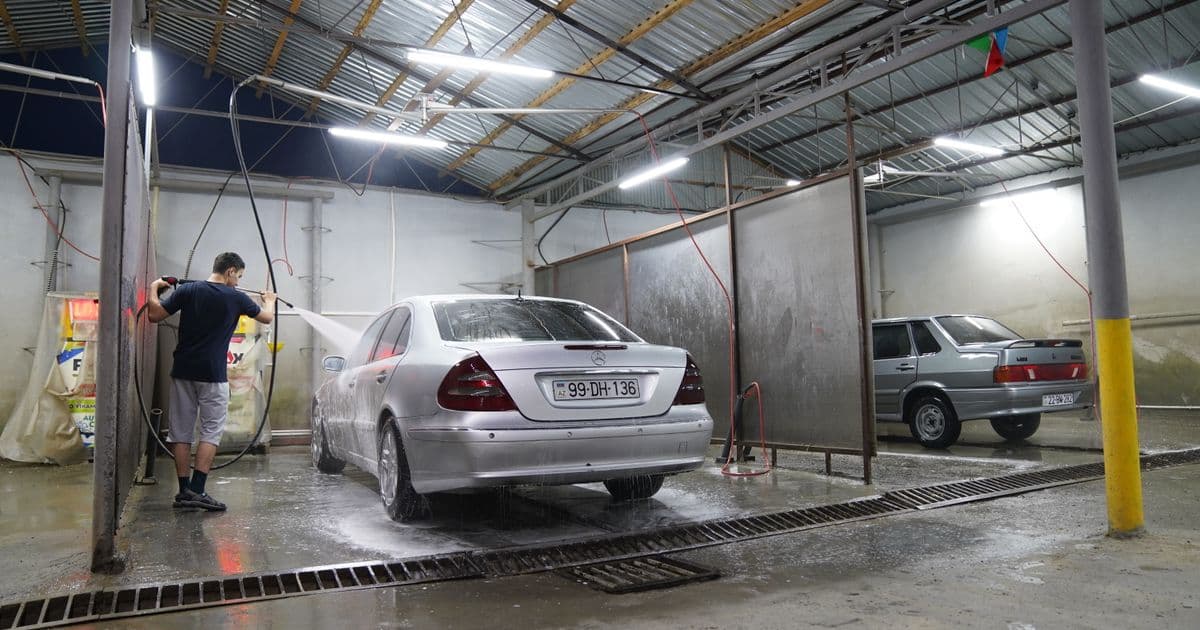 Operator running a pressure washer in a covered work area — solo pressure washing business at work